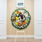 Pésame para un amigo con lirios de colores en arreglo floral de luto